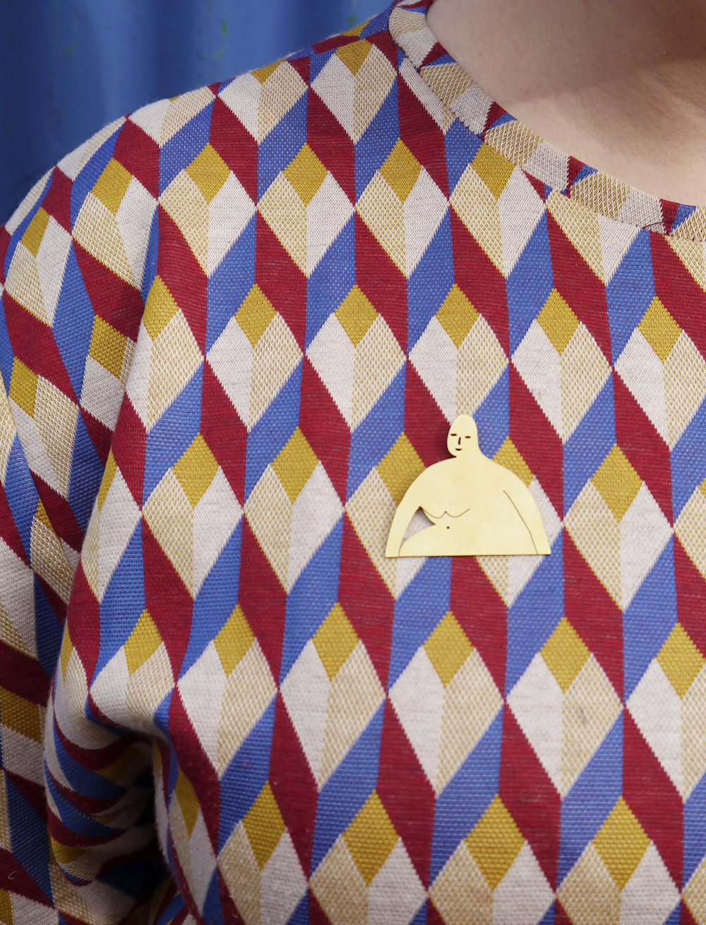 Brass pin shaped like a woman worn on a geometric patterened dress