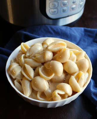 bowl of macaroni and cheese in front of pressure cooker