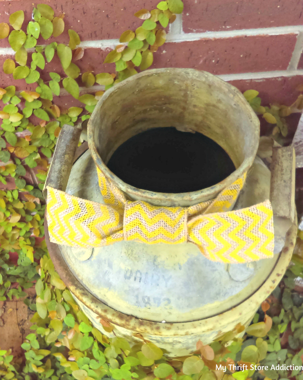 Repurpose a vintage milk can as a whimsical scarecrow by adding a pumpkin head, burlap and raffia accents. repurposed vintage milk can scarecrow