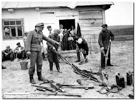 A German soldier orders Russian civilians gather captured Soviet arms.