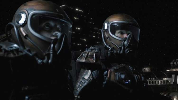 Young and Greer don space suits in SGU's "Divided".