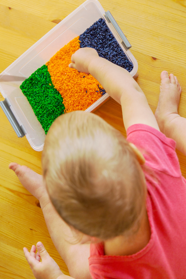 Have all the fun of play sand without all the mess with this rainbow rice recipe for kids!  You can make make rice in every color of the rainbow, and ricewon't mush into carpet like play dough. #rainbowrice #rainboericesensory #coloredrice #coloredricesensorybin #dyedrice #dyedricesensory #howtomakerainbowrice #ricerecipes #riceplayfortoddlers #growingajeweledrose