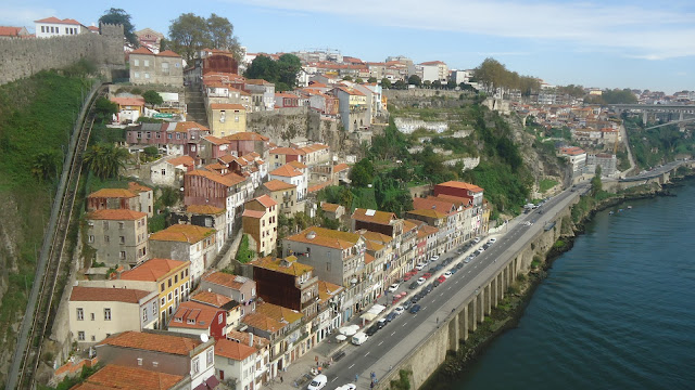 Porto com um pedaço da muralha Fernandina à esquerda e o funicular dos Guindais que liga as a parte alta da parte baixa do Porto. Ponte de D. Luís I - que ver em Porto, Portugal.