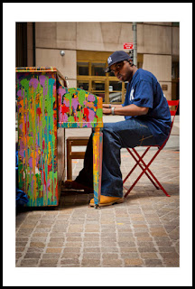 a photograph of a man playing a brightly painted piano on the street in new york