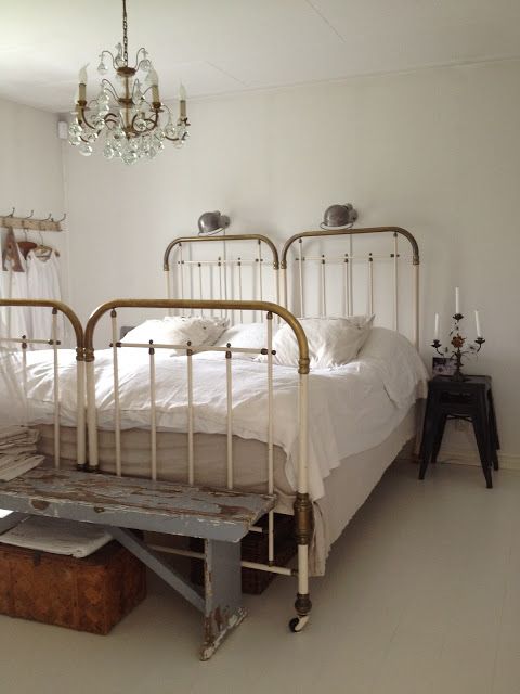 An authentically French Country bedroom with vintage twin beds pushed together, farm bench with peely paint, and crystal chandelier. #frenchcountry #shabbychic #vintagebed
