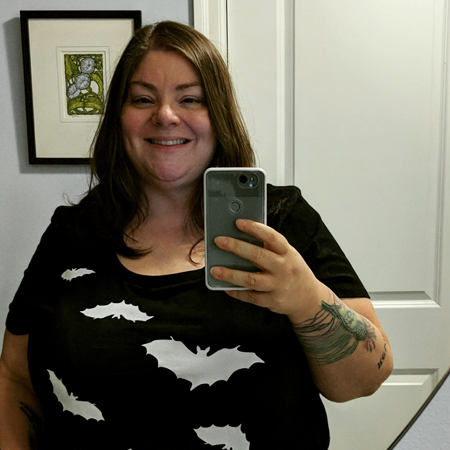 image of me from mid-torso up, standing in a mirror wearing a black t-shirt with a pattern of white bats on it