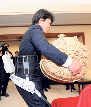 SEORANG pekerja Cyberdyne mengangkat beg jerami yang mengandungi beras seberat 65 kilogram di sebuah pejabat di Niigata semalam. 