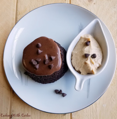 These mini chocolate cakes are moist and delicious. They are the perfect single serve size to quench that sweet tooth craving. Add a dollop of peanut butter whipped cream to take them to the next level. The best part is the batter is from scratch and comes together in just a few minutes. upside down chocolate cupcake with chocolate glaze, mini chocolate chips and a little leaf shaped bowl of peanut butter whipped cream