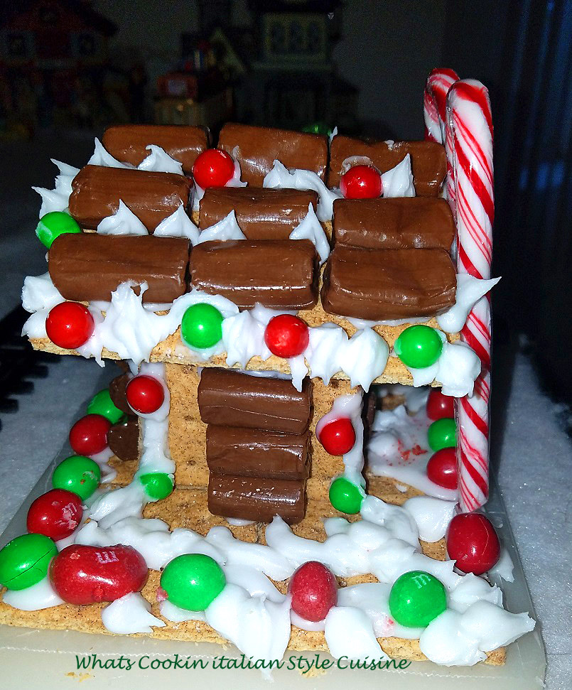 this is an adorable little house kids can make their own individual personalized  at Christmas with the candy cans, colored coated green and red candy, santa, marshmallows, graham crackers with cinnamon, powdered sugar frosting that is the glue,and tootsie rolls for the look of a log cabin