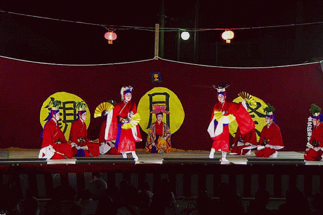 Women with gold fans, dressed in red kimonos, dancing