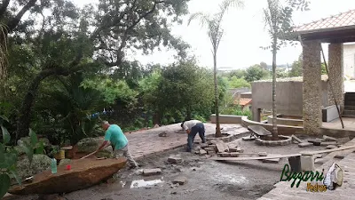 Execução do calçamento com pedra folheta com os redondos de paralelepípedo nos pés das árvores com colocação do banco de pedra natural com a execução do canteiro com pedra no jardim em residência em Itatiba-SP.