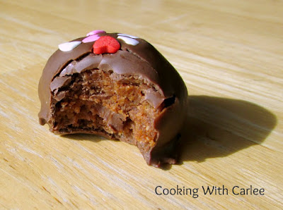 These sweet little rum balls will make you feel the burn! Perfect for your Valentine or as a holiday treat. They are a little bit nice with the chocolate and a little bit naughty with the booze! bite missing from a chocolate dipped rum ball