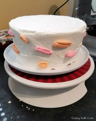 white iced "cake" with dots of orange and pink frosting randomly on it