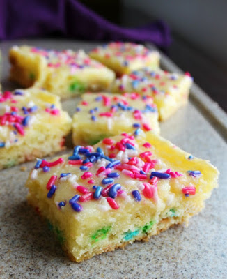 The goodness of gooey butter cake only made more fun with sprinkles! This is a fun birthday or party treat that is super easy to make and oh so gooey and delicious! Pieces of gooey butter cake on a cutting board