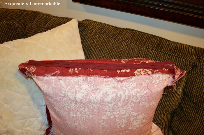 Red pillow on a couch with cover turned inside out to add a zipper