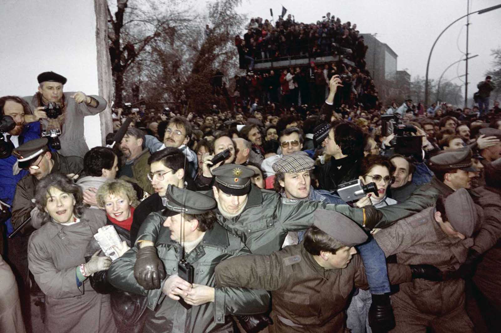 East and West German Police try to contain the crowd of East Berliners flowing through the recent opening made in the Berlin wall at Potsdamer Square, on November 12, 1989.