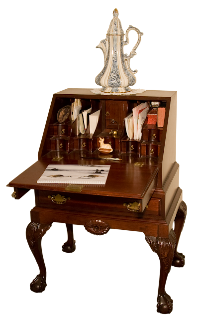 A reproduction Chippendale-style drop-front desk, with highly detailed carving and wooden ball-feet. Made in cherry wood.