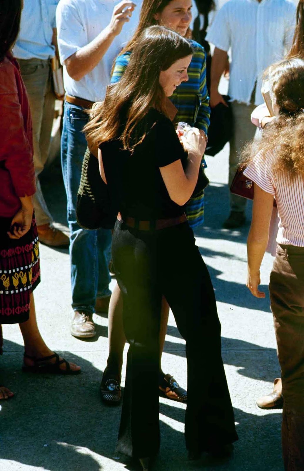 A high school student among other classmates while wearing black bell bottoms.