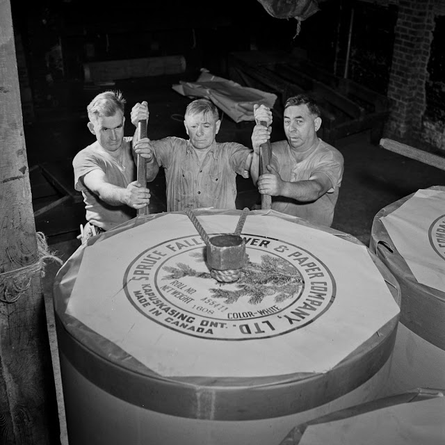In the reel room, pressmen transport a 1608-pound paper reel to the presses. The reel has enough for about 1300 newspapers.