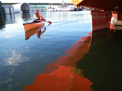 nigel foster, reflection of red ship hull and blue sky, with canoe