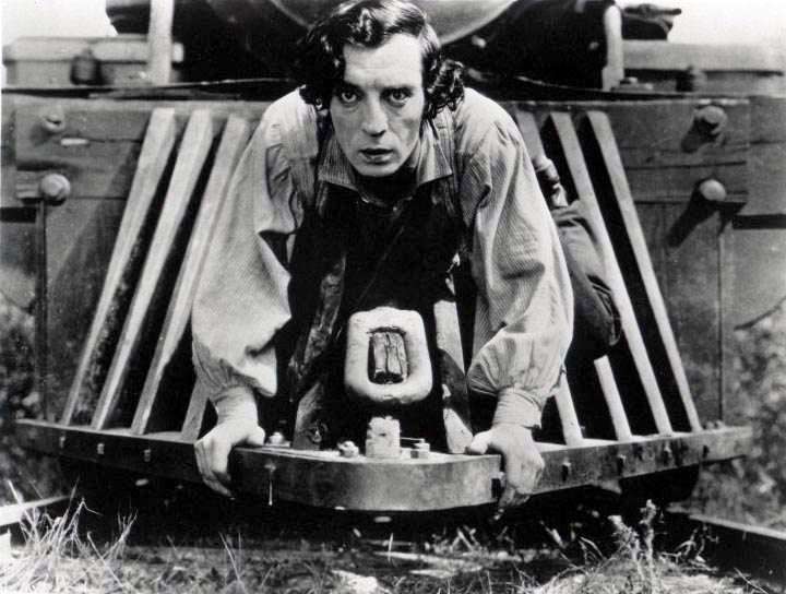 Fotograma del Maquinista de la General que muestra a Buster Keaton subido en una locomotora al borde del suelo y las vías