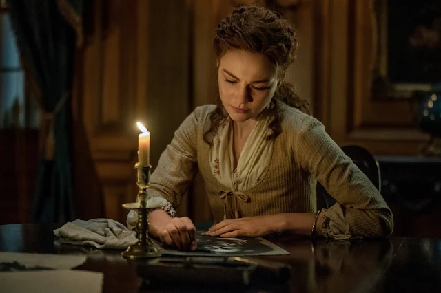 Brianna at a desk with a quill in Outlander Episode 411