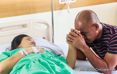 Hombre orando por mujer enferma en hospital