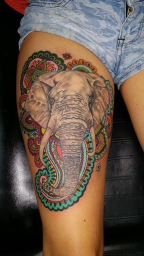 Um elefante que se parece com o seu acaba de cair um mau guia de ácido é rodeado por um colorido matriz de padrões nesta vibrante tatuagem.