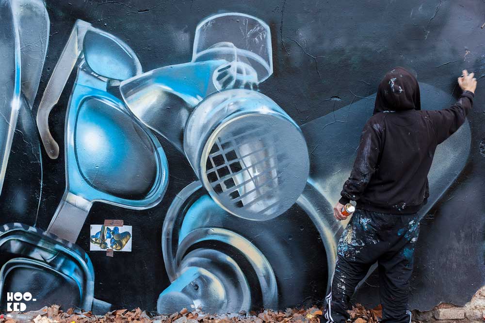 London street artist Fanakapan paints a mural in East London's Star Yard car park.
