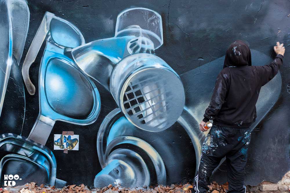 London street artist Fanakapan paints a mural in East London's Seven Star Yard car park.
