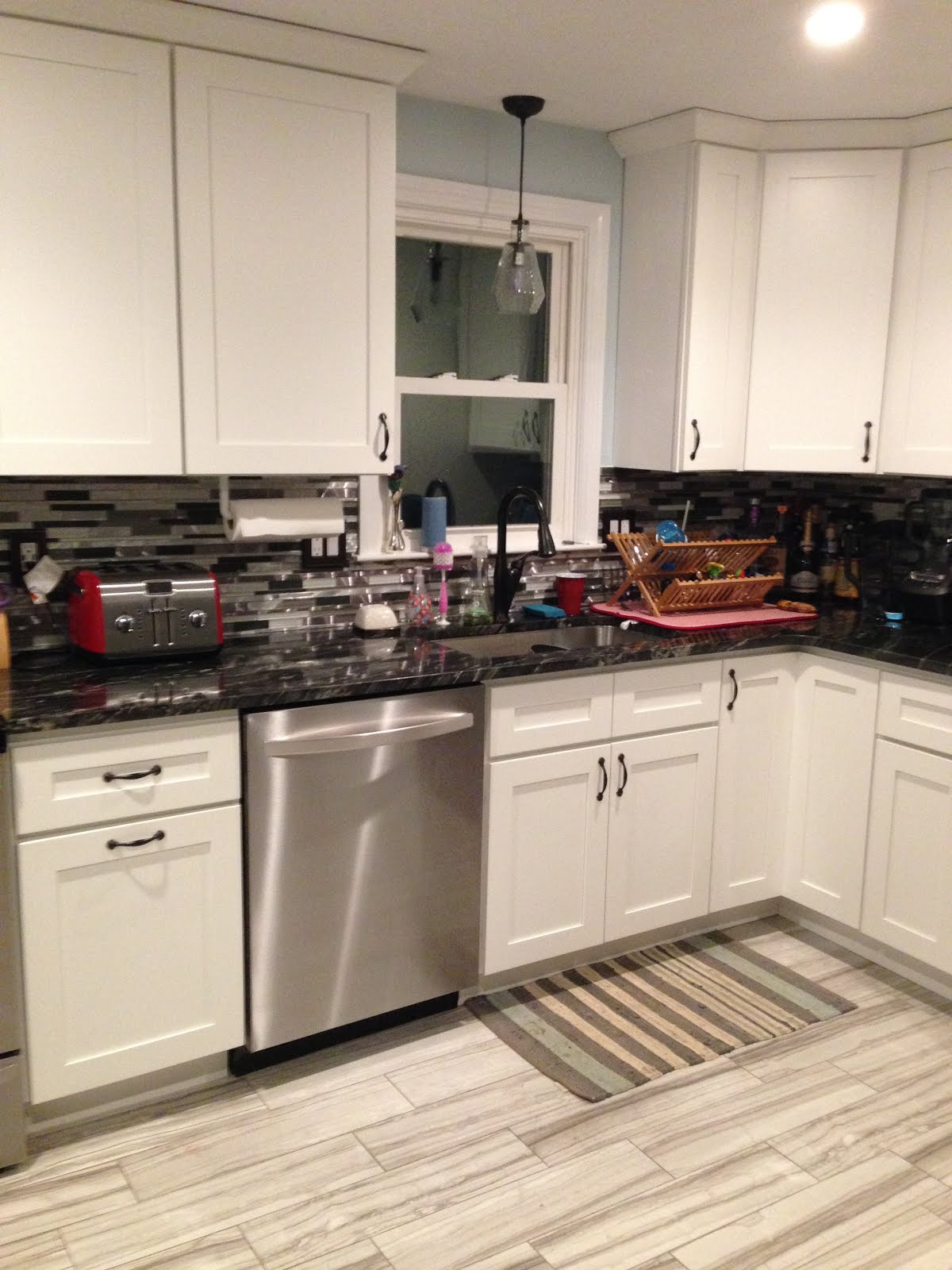 updated kitchen with white cabinets, black countertops, and stainless steel appliances