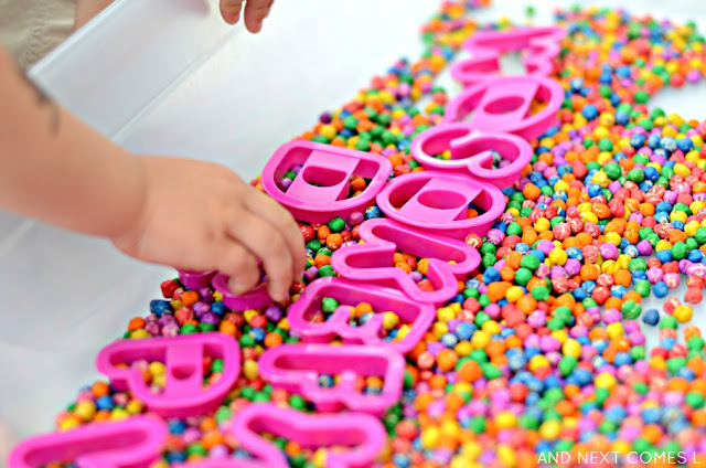 Sensory & literacy activity for kids using rainbow dyed chickpeas and alphabet cookie cutters from And Next Comes L