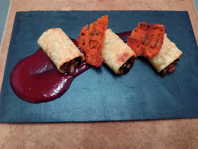 Paccheri (o canelones) rellenos de conejo confitado y setas de cardo, con salsa de cerezas y crujiente de pesto rojo.