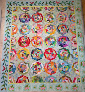 Cardinal rest on the applique vine border of this scrap spiderweb quilt.