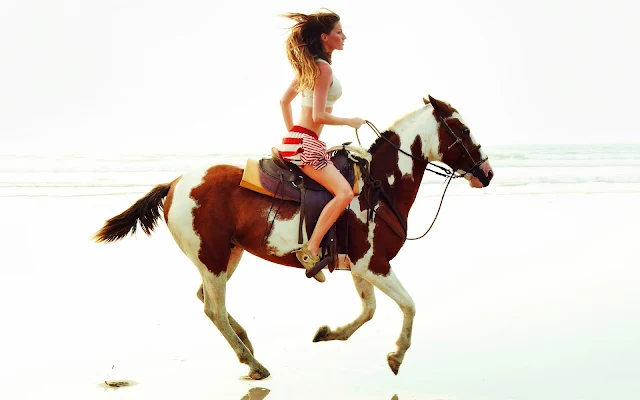 Vrouw rijdend op een bruin wit paard op het strand