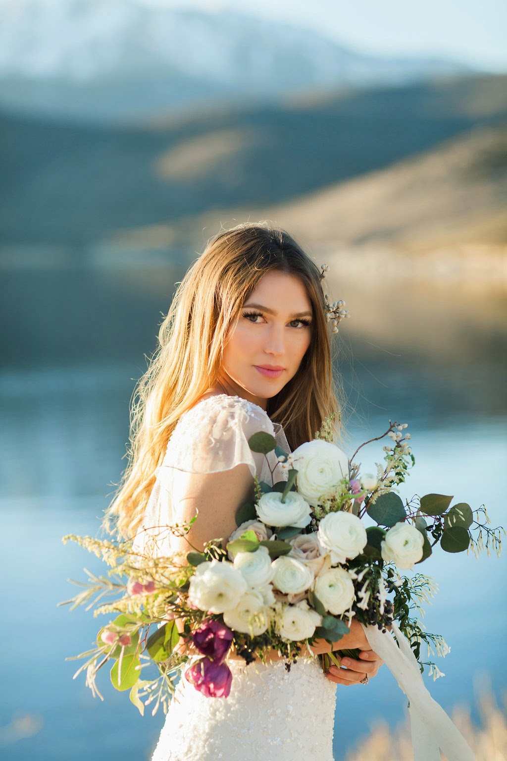 beautiful lakeside bride in a beaded flutter sleeve dress with tallow berry hairpiece and a late winter white and purple bouquet tied with hand dyed soft blue silk and willow ribbon