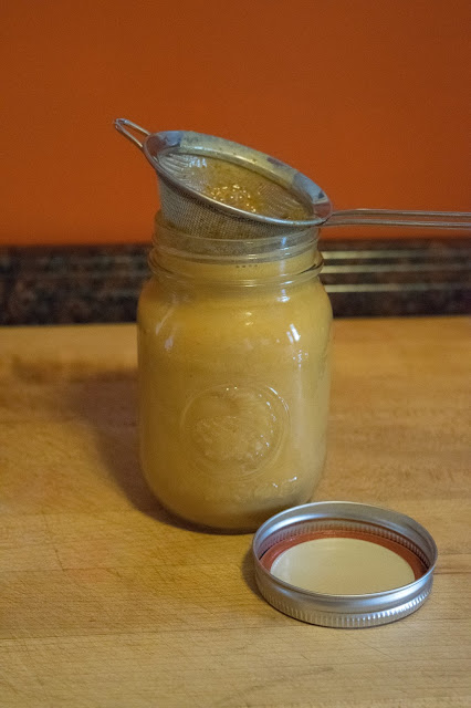 A mason jar, filled with creamer, with a sieve on top of it. 