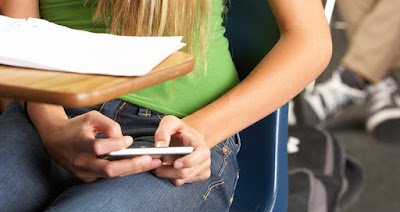 adolescente usando celular a escondidas en salón de clases