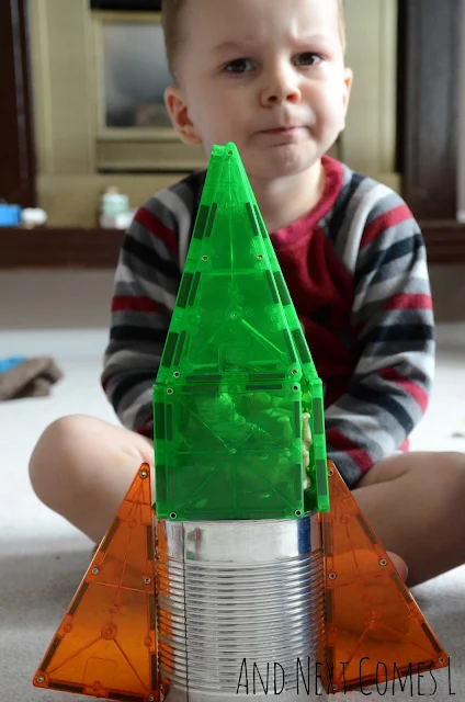 A toddler with his finished tin can and magna tiles rocket ship