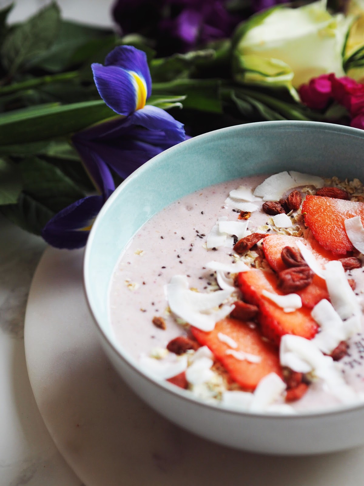 Chia Berry Smoothie Bowl close up of toppings, strawberries, coconut flakes, chia seeds and goji berries