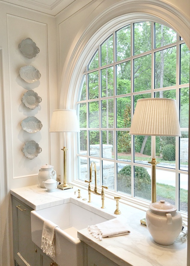Stunning kitchen with arched window above farm sink and glazed blue plates on wall
