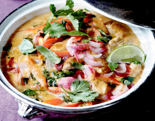 Classic Thai red chicken curry cooked in a casserole and served garnished with coriander leaves and lime wedges