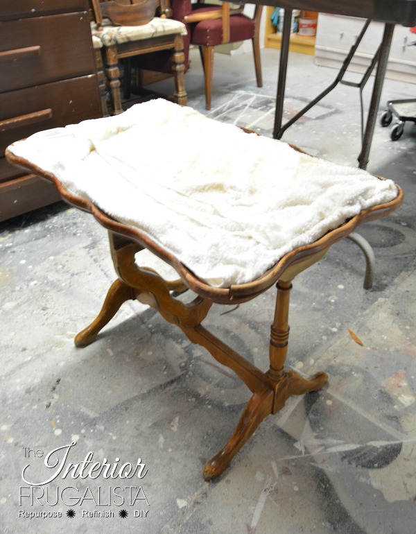 Removing damaged veneer from an antique tilt-top table with wet towels.