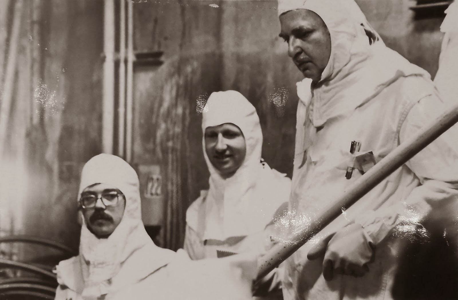 A black and white photograph of three men in protective gear. 