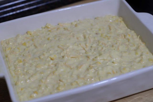 The corn casserole in a greased baking dish. 