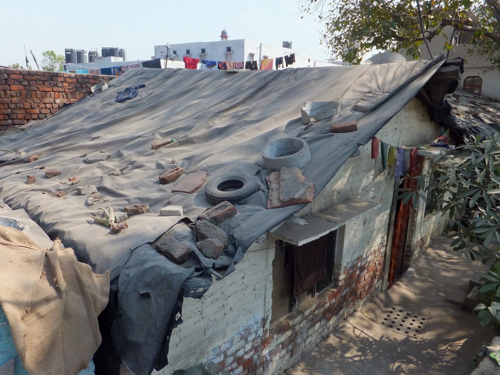 крыша покрытая брезентом и заваленная тротуарной мусором и шинами
