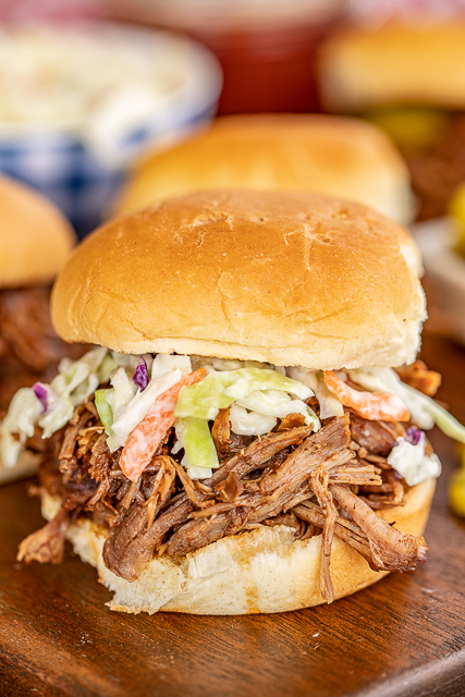 Slow Cooker Maple Chipotle Beef Sliders - seriously delicious!! Chuck Roast slow cooked in a combination of pineapple juice, maple syrup, tomato paste, and chipotle peppers. Sweet and smoky in every bite! Serve on slider buns or on top of nachos or a baked potato. Can freeze for a quick meal later! Great for potlucks, parties and tailgating! #crockpot #slowcooker #freezermeal #beef #potroast #sliders shredded beef sandwich topped with colelaw