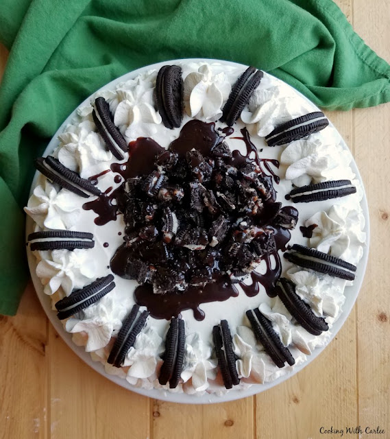 Cookies and cream ice cream cake is full of chocolate and vanilla ice cream, but the fudgy crunch center ribbon is the real star of the show. Kick up your feet and cool down with a slice! top of ice cream cake with chopped oreos, fudge drizzle, whipped cream etc.