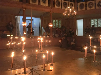 photo showing interior of Sam Wanamaker playhouse, with lit candles in chandeliers
