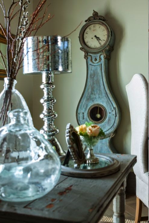 Weathered painted Swedish antique clock in a living room. Come see this Rustic Elegant French Gustavian Cottage by Decor de Provence in Utah! #frenchcountry #frenchfarmhouse #interiordesigninspiration #rusticdecor #europeanfarmhouse #housetour